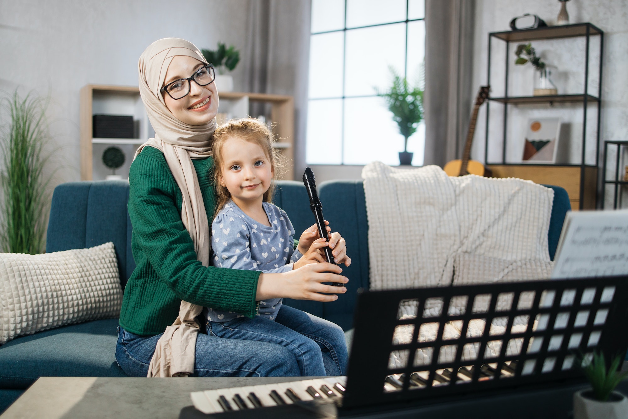 Little cute girl with music muslim teacher having lesson at flute at school of music.